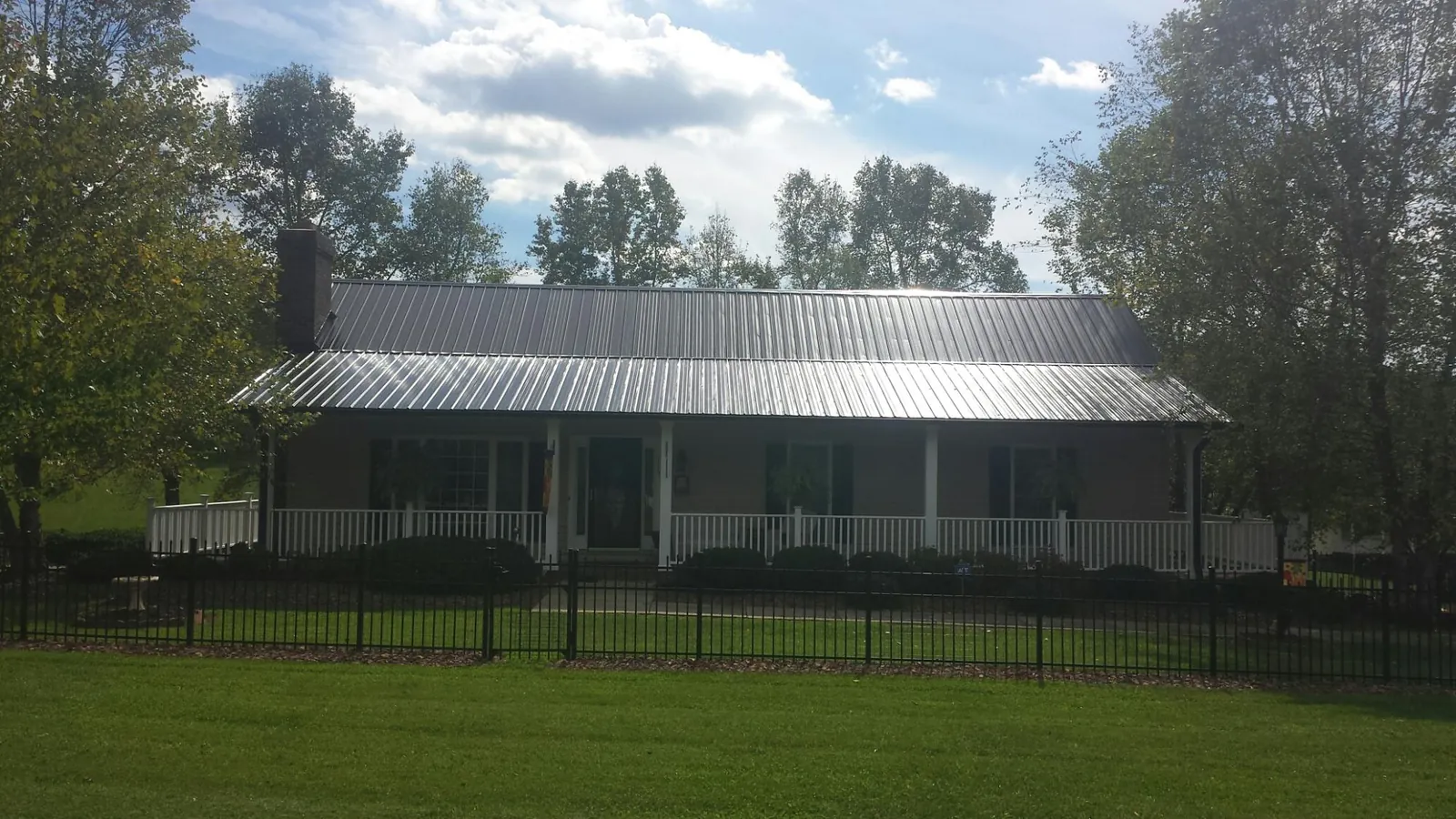 Gray metal roof on a brick ranch with a full width front porch — Gutter Guard Installation work by our crew in Fort Lee