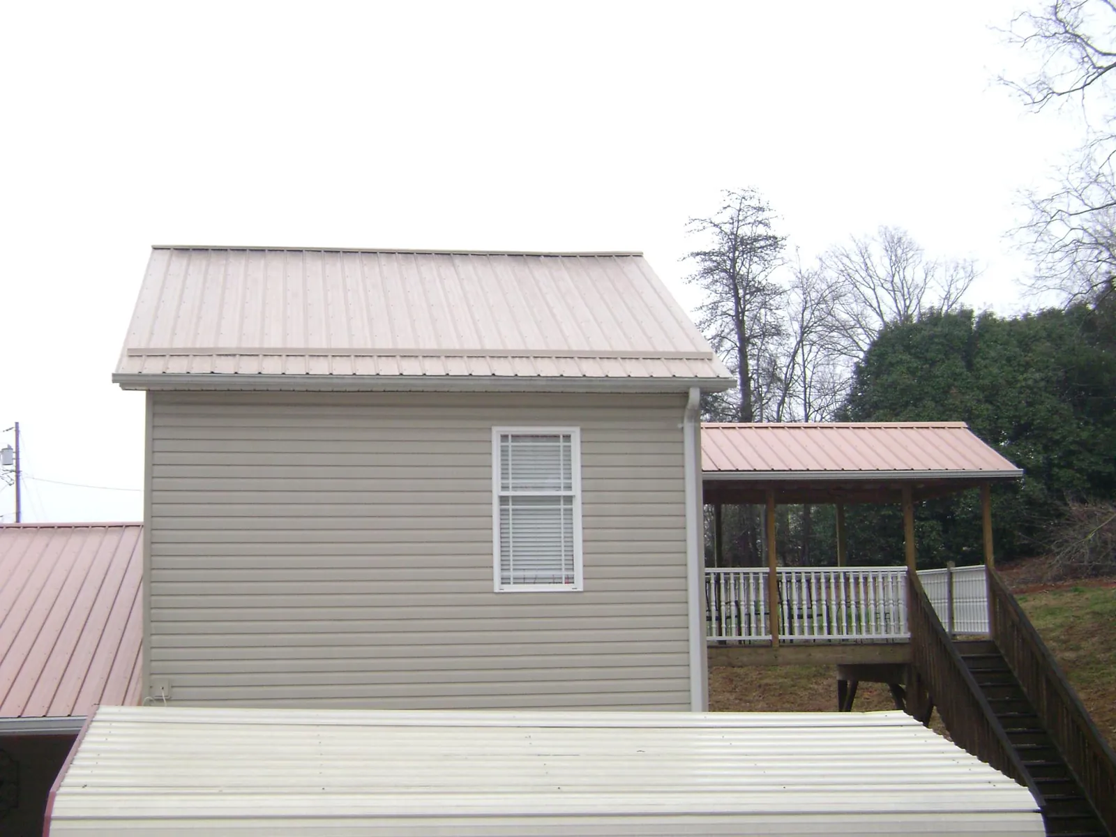 Tan metal roofs on a two story addition and attached porch, from a Roof Replacement job in Fort Lee