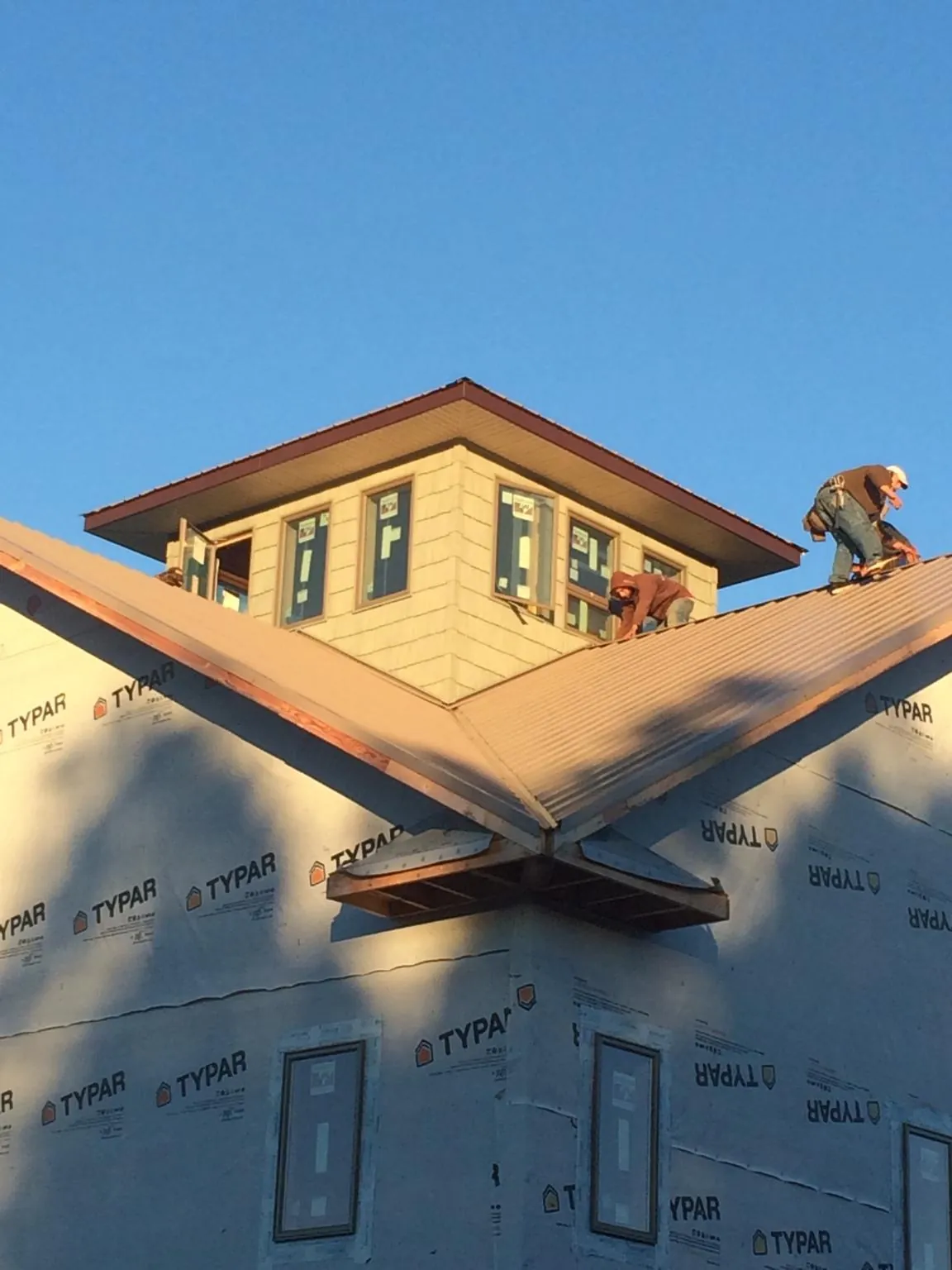 Roofers working around a rooftop cupola on a new metal roof at sunset — Roof Waterproofing in Fort Lee by Roofing Brothers